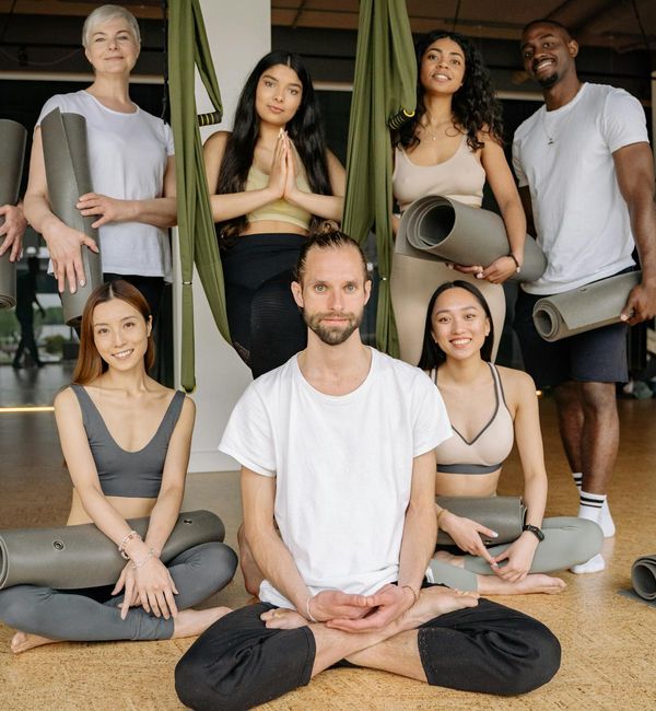A diverse group of people sitting on yoga mats and smiling.